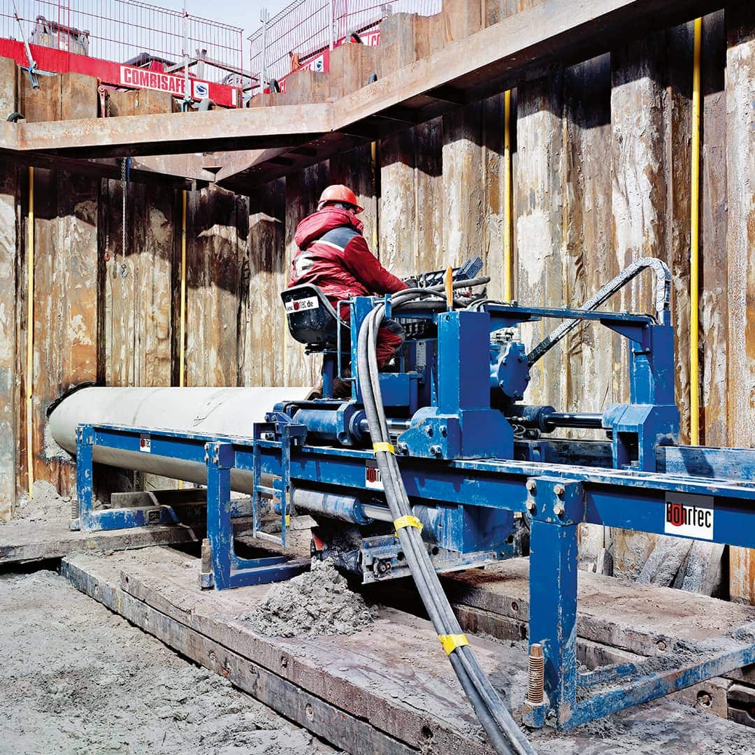建筑工地的工人在地面上控制一台蓝色的 Bohrtec 机器。
